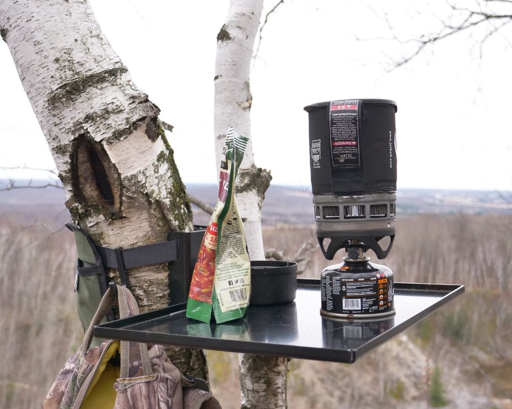 Top Shelf camping and outdoor table set up on a tree, overlooking vast landscape, and preparing a backpacking meal.